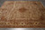 Angled floor view of beige Agra wool rug with all-over floral field and burgundy stripes