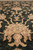 Pile-level close-up of apricot palmette with sage green center on charcoal black field