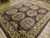 Burgundy and antique gold traditional Agra wool rug photographed from the corner on hardwood