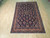 Navy blue Sarouk rug laid flat on pale hardwood floor showing dense all over floral design