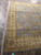 Angled corner view of light blue and gold Oriental area rug with cotton fringe