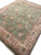 Corner to corner view of moss green wool rug with tan border and brown rosette vines