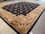 Angled showroom photo of modern black and gold wool rug with notched stepped field outline