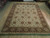 Vegetable dyed wool rug in showroom setting, cream palmette field framed by deep brown border
