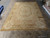 Showroom floor photo of neutral beige Aubusson rug showing rose bouquet medallion and wide brown border