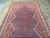 Hand-knotted wool pile seen from above, navy medallion flanked by red field of tribal ornaments