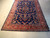 Full length showroom photo of the blue and coral floral rug with ivory fringe