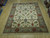 Hand-knotted wool rug shown flat on wood floor, ivory field with rust and sage leaves