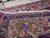 Coin resting on pile shows weave scale, dense wool knots and border flower detail