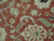 Close-up of hand-knotted wool pile showing cream palmette, sage serrated leaves and terracotta rust ground