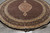 Angled view of 8 foot round rug showing ivory fringe, black border and Herati fish field