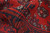 Macro of dense red wool pile with cream accents in the Bokara gul pattern