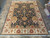 Full 9' x 12'9" Agra rug on tile floor showing dark navy field and cream border