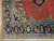 Corner of the rug showing cream spandrel, navy border palmettes and ivory fringe on wood flooring