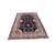 Rug photographed at an angle on a white floor, navy field and rose border receding