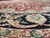 Low angled close view across the pile where the red field meets the dark border scrollwork
