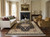 Black and ivory Tabriz rug anchoring cream sofa, gold armchairs and marble fireplace living room