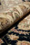Rolled edge showing plush wool and silk pile depth beside the black floral field