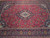 Close view of lobed ivory and blue medallion surrounded by scrolling floral vines in red