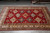Angled showroom view of red Oriental rug with multiple ivory and saffron guard borders