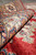 Close detail of soft silky wool pile where the ivory border meets the ruby field