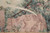 Pink stone fountain relief with cherub carving framed by teal leaves and arching water