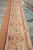 Salmon and ivory border detail with repeating palmette scrollwork along the tapestry edge