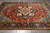 Coral red medallion field photographed from above on grey tile floor, hand-knotted wool Serapi design