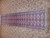 Long narrow wool runner photographed sideways, rose pink field, charcoal borders, rolled section at right