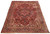 Angled floor display of 8x10 hand-knotted Heriz rug with charcoal border and rust red field