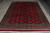 8' x 11' Bokhara rug seen at an angle, full gul lattice across the deep red field