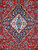 Close-up of ivory and navy lobed medallion with blue rosette on deep red ground