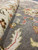 Pile close-up at a folded edge revealing dense wool knots and coral floral outlines