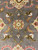 Macro of a 10 petal rosette in gold, coral and ivory on gray wool ground