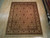 7'10" x 9'8" hand-knotted Indian rug displayed on light wood showroom floor, ivory borders