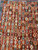 Close-up of multicolored hexagon lattice motifs in saffron, teal, aubergine and ivory on rust ground