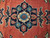 Close-up of navy medallion with blue rosettes, coral palmettes and ivory outline on red field