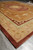 Low corner angle showing deep wool pile, sage meander guard band and rust outer edge