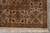 Corner detail with camel border, green palmettes, brick red rosettes and ivory fringe tassels