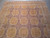 Looking down the length of the rug at repeating gold medallions across the mauve field