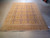 7'8" x 10' wool Oushak rug displayed in full on a warehouse floor with ivory fringe