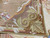 Close-up of gold acanthus scroll corner and rust border on hand-woven needlepoint rug