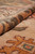 Rolled edge close-up highlighting pile depth, warm tan ground and golden ochre floral motif