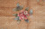 Detail of a pink peony bloom with sage leaves on carved blossom lattice ground