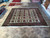 Showroom floor view of the square light green wool rug among other hand-knotted rugs