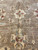 Center axis close-up of cream palmette and vase motif framed by thin vine scroll