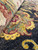 Close-up of a gold palmette on the black ground, showing wool sheen and knot definition