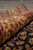 8x10 hand-knotted rug rolled back to show dense gold border pile and paisley motifs