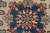 Macro of the navy medallion centre, eight-point rosette in red, green and tan on ivory