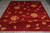 Rug lying flat on grey flooring, short side forward, gold flowers across the burgundy field